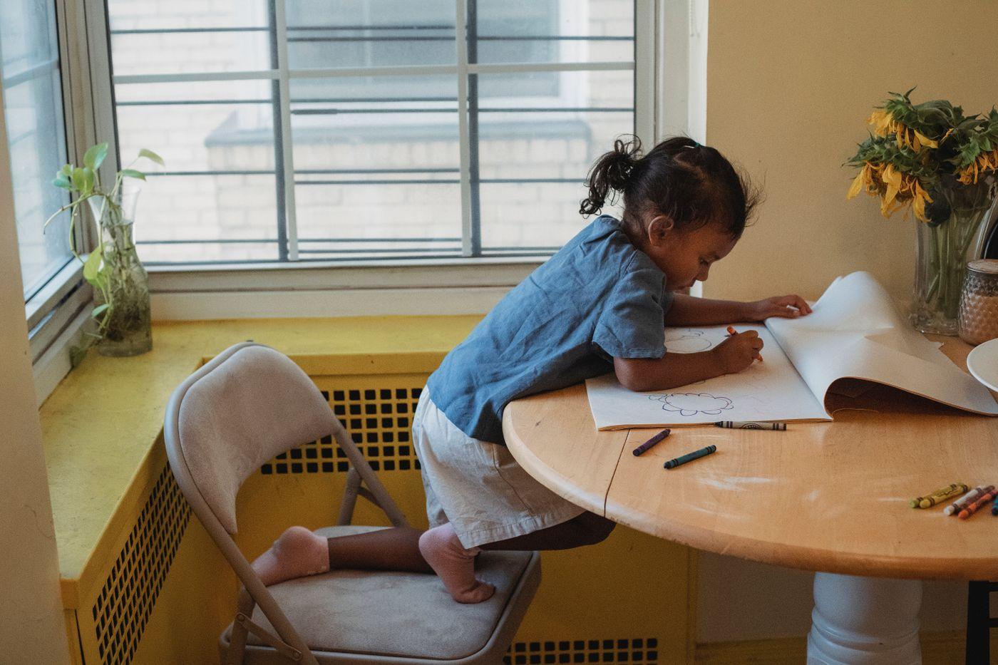A young learner concentrating on a drawing at a sunlit table